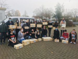Die Klasse 6b nimmt die Boxen von Frau Dr. Sabine Meßmer-Luz (rechts stehend) entgegen.